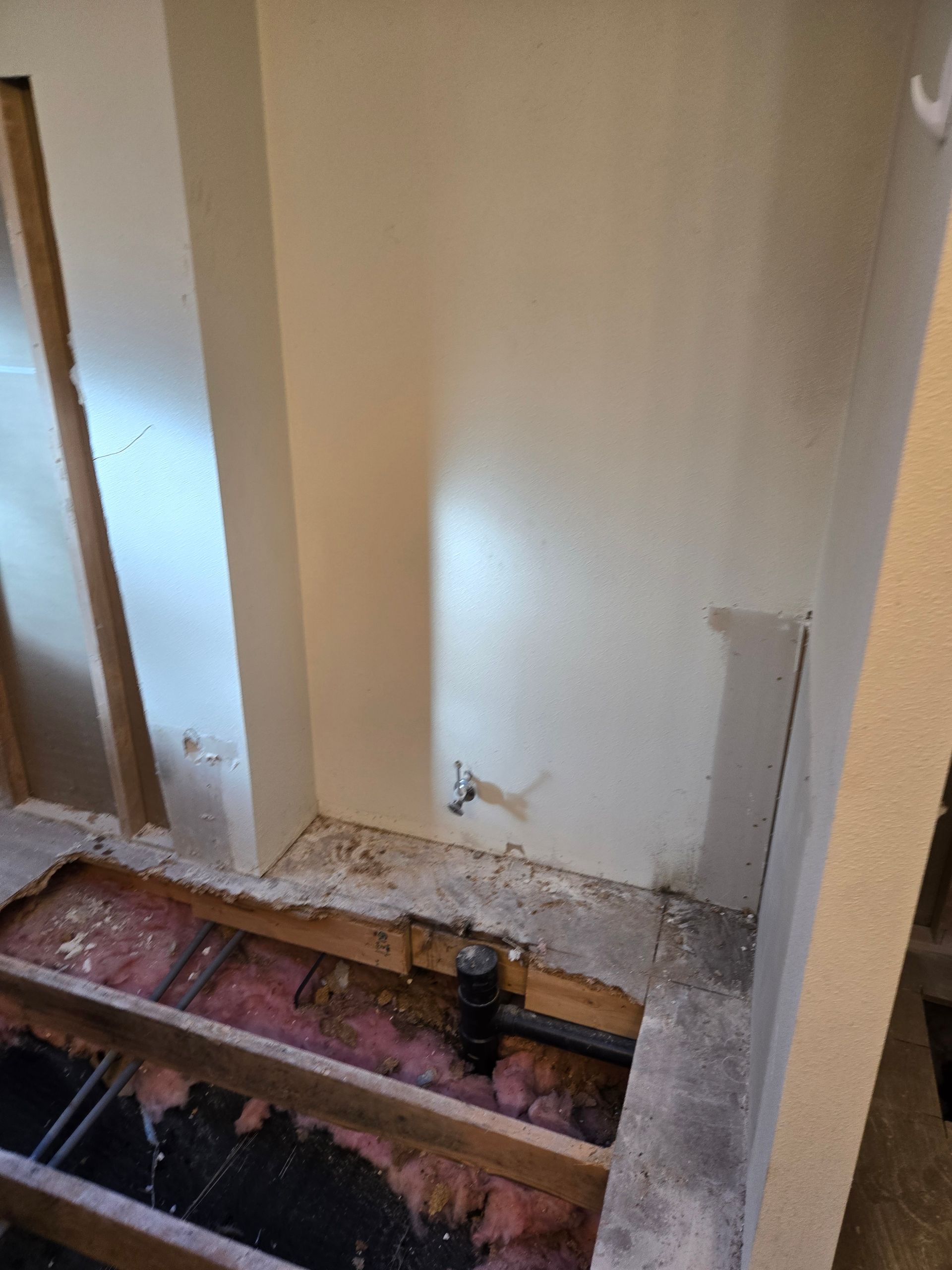 Partially demolished room floor with exposed joists, debris, and bare wall studs