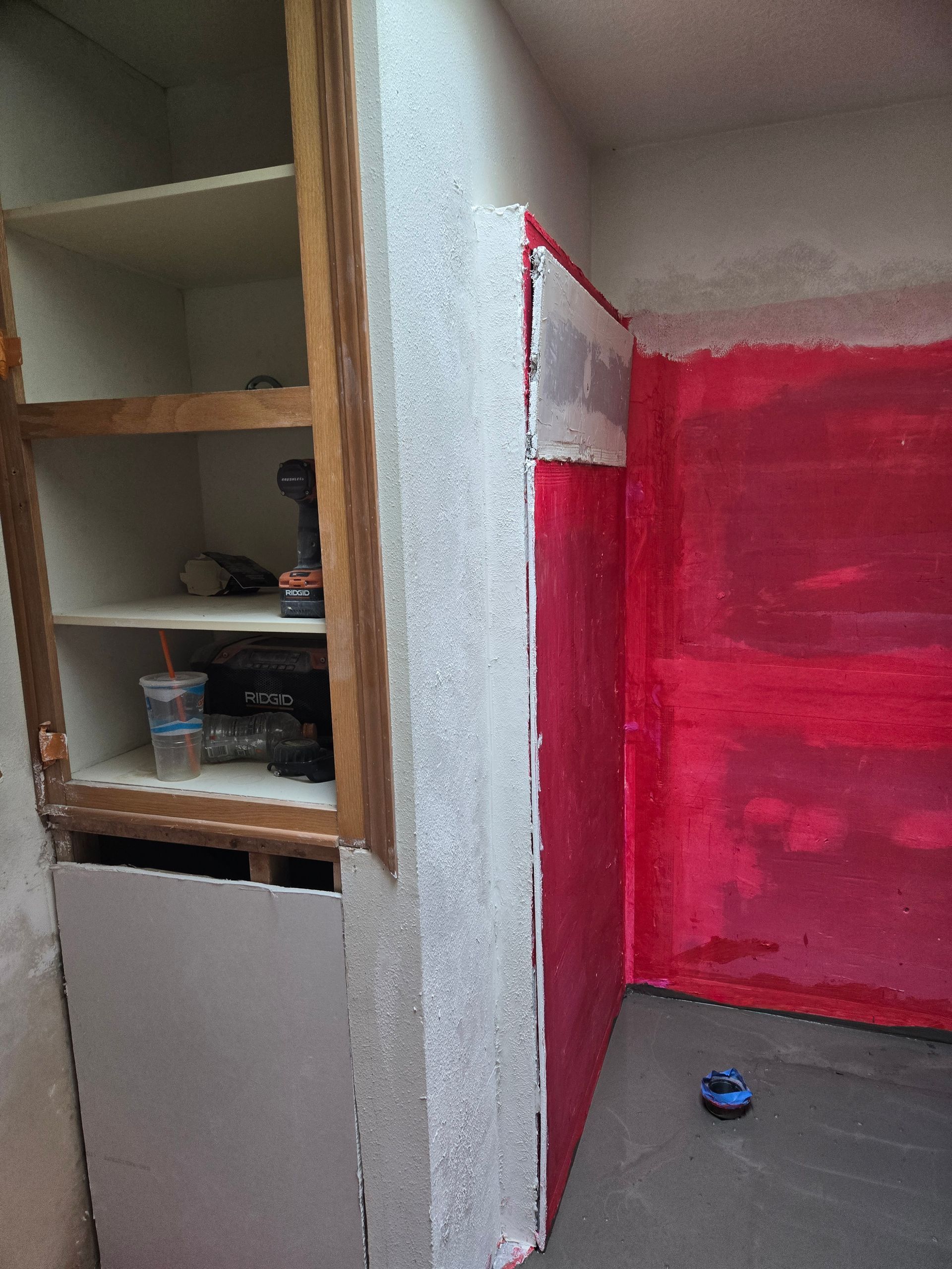 Interior room with red walls, a gray floor, and open wooden shelves on the left.