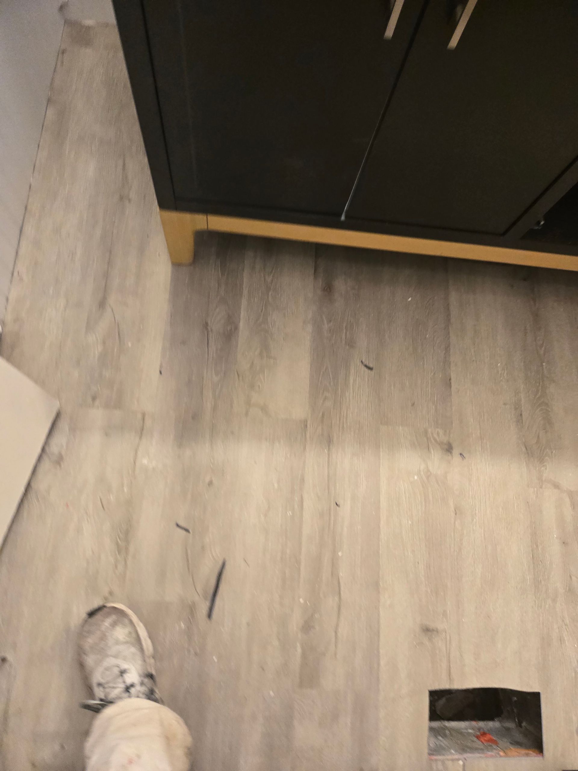 Indoor floor with a shoe at bottom left and a small wall hole near a dark cabinet.