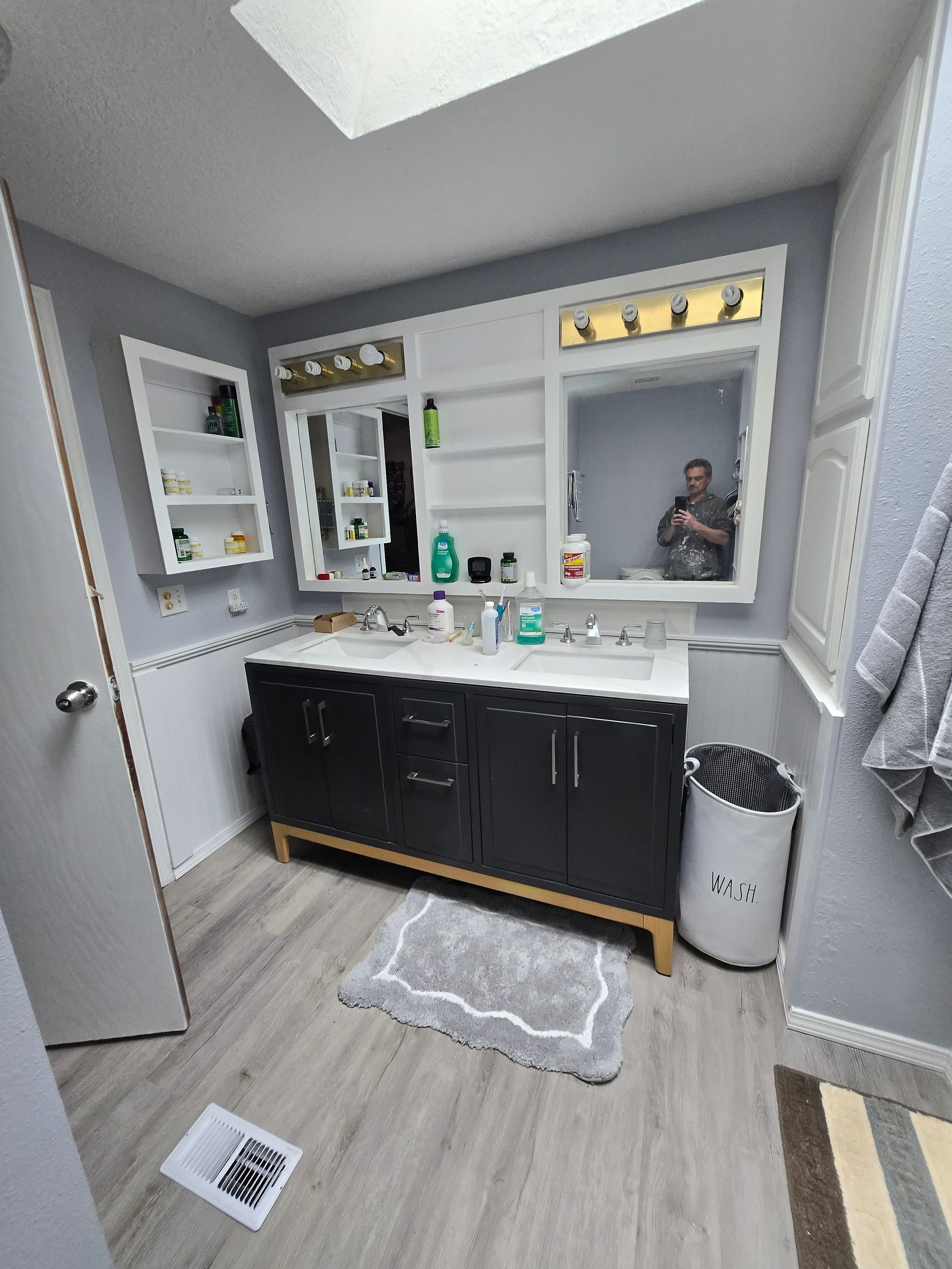 Small bathroom with dark vanity, mirror, sink, toilet, gray walls, and wood-look floor.