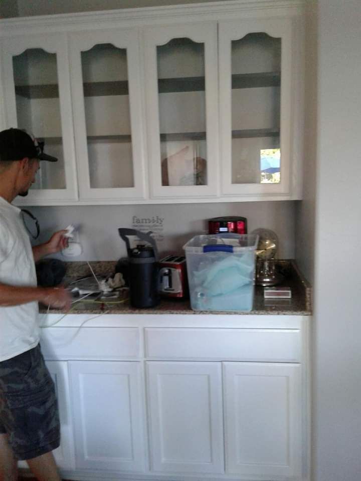 Person standing at a kitchen counter beside white cabinets and a coffee maker.