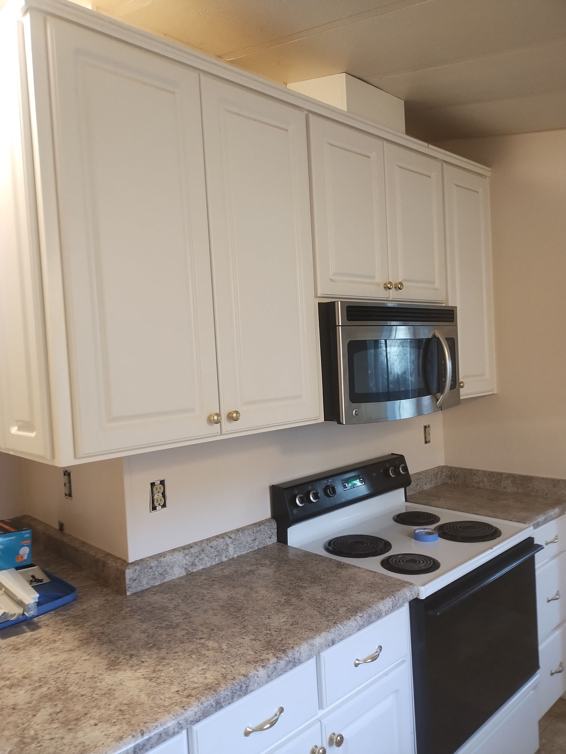 White kitchen with granite countertops, stove, microwave, and cabinets along the wall