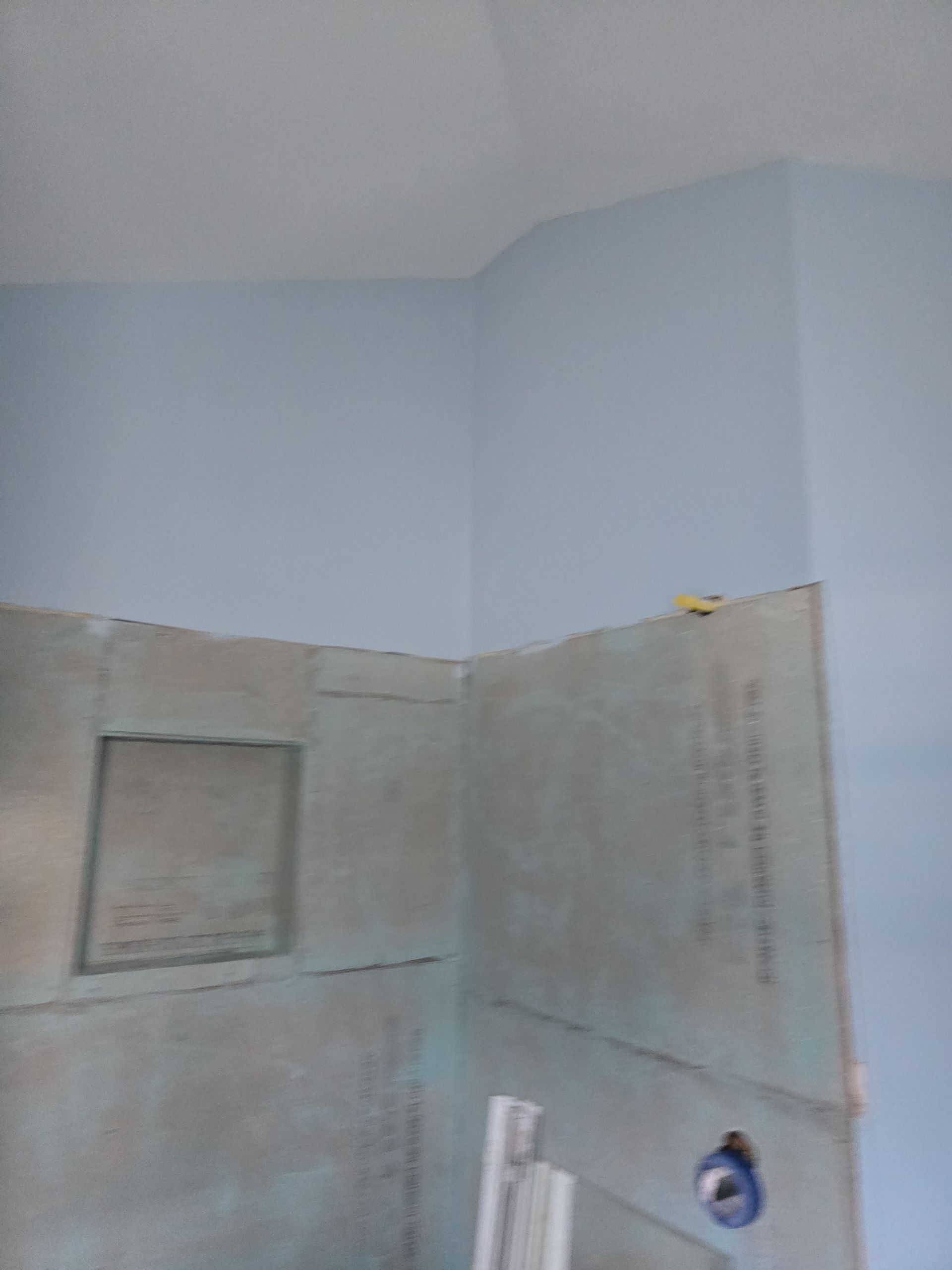 Partially tiled bathroom wall with light blue paint, built-in shelf, and plumbing fixtures under renovation
