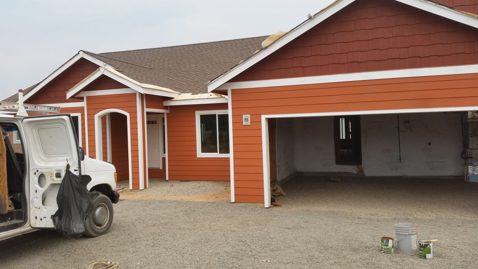 Orange house exterior with white trim and open garage, with a white van parked in front