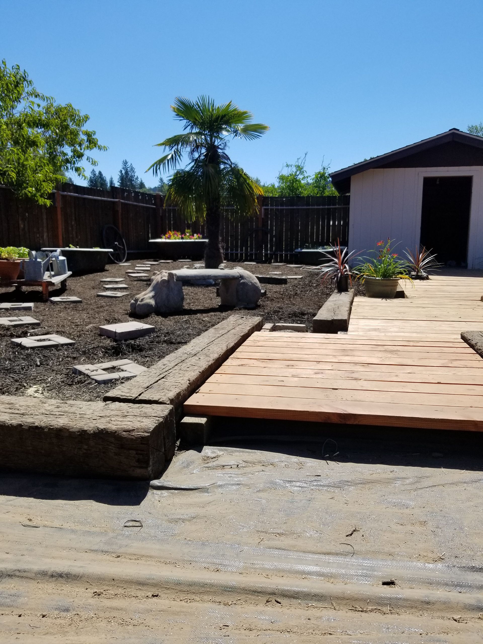 Outdoor yard with stone and paver landscaping under construction beside a house.