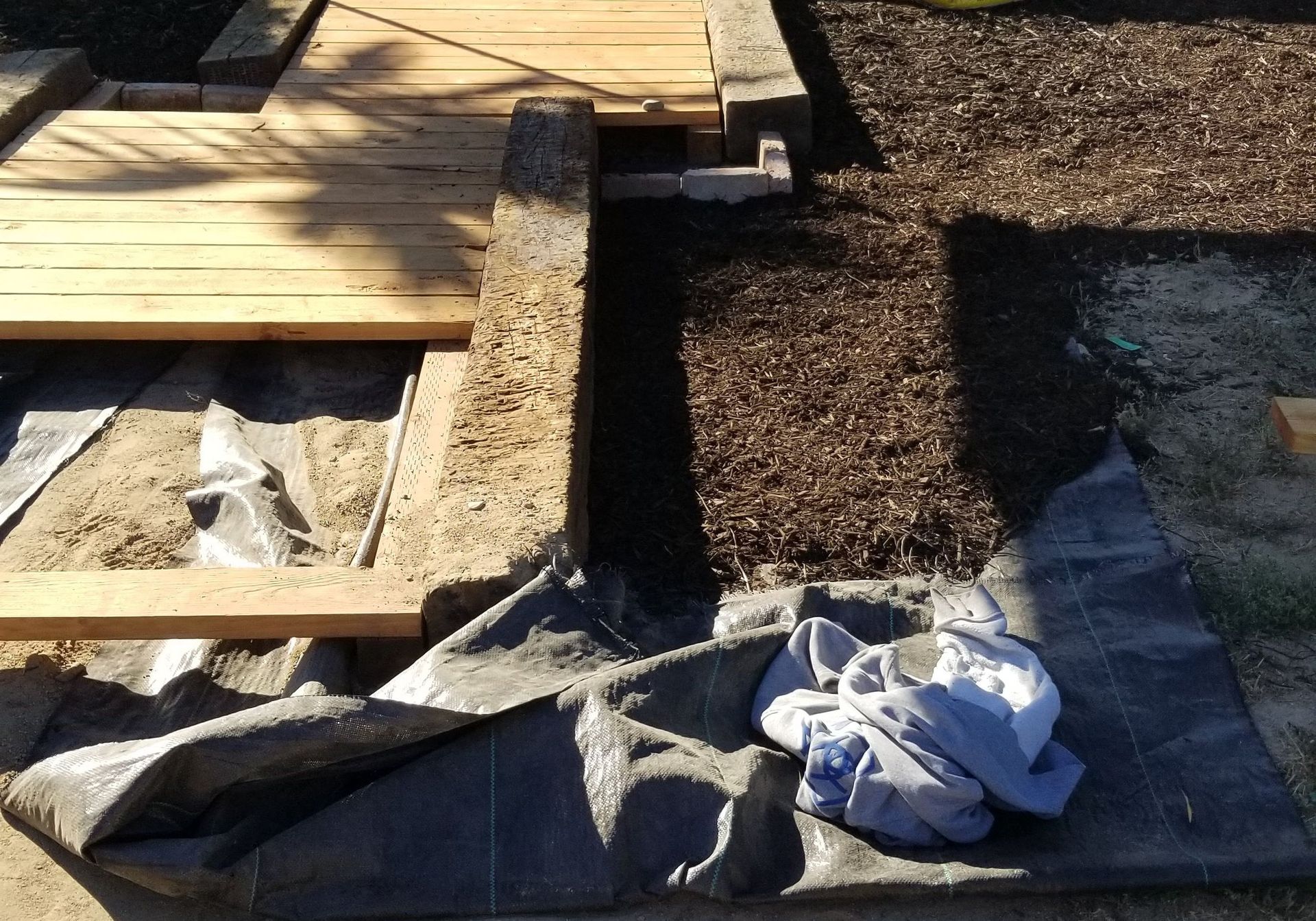 Roofing work area with plywood, tar paper, gravel, and tools on a rooftop under construction