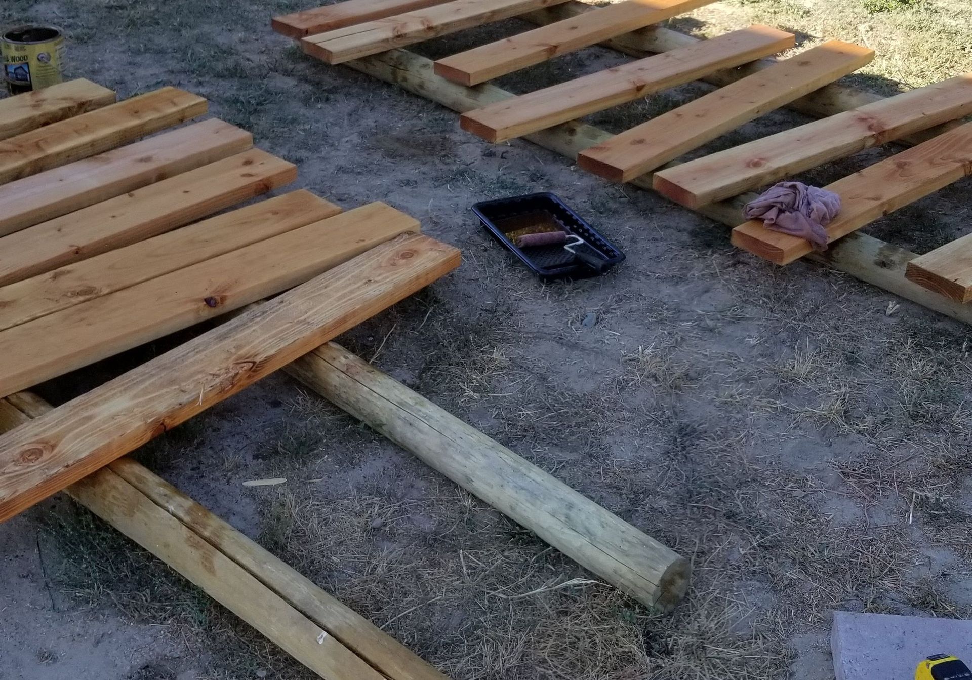 Wooden pallets laid out on gravel with a small black tool and a purple block nearby.