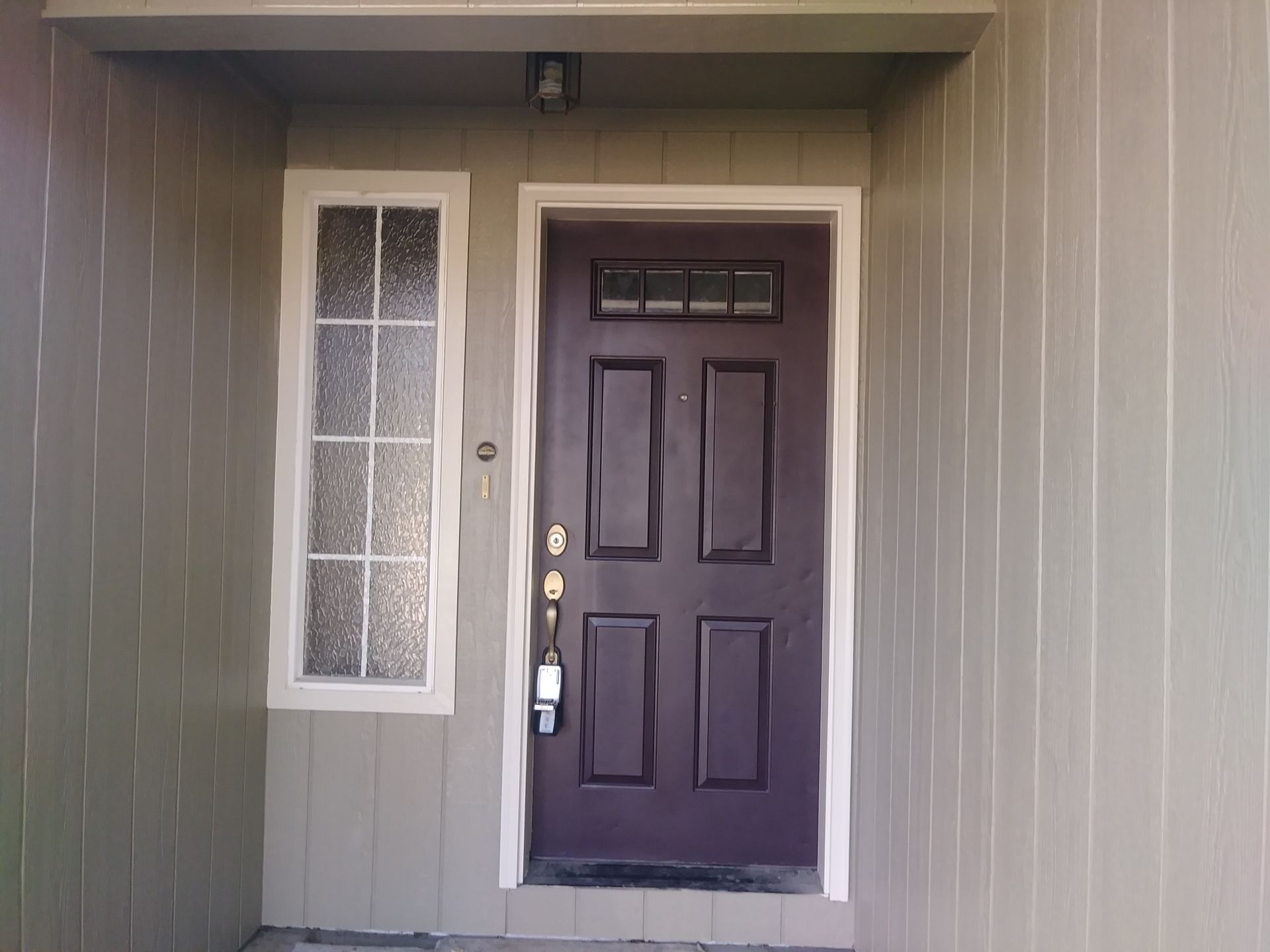 Front porch with a dark front door and a narrow frosted window panel beside it.