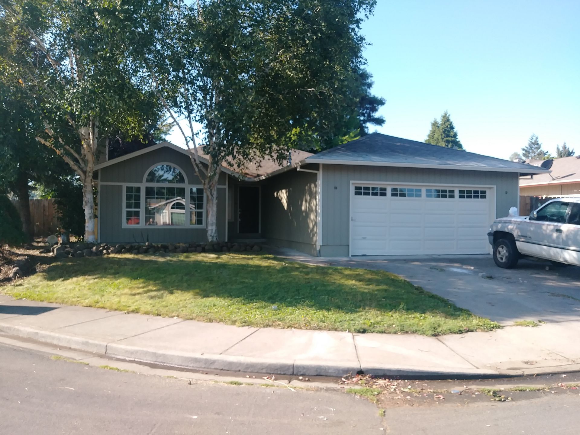 Suburban house with two-car garage, front lawn, and a pickup truck parked in the driveway.
