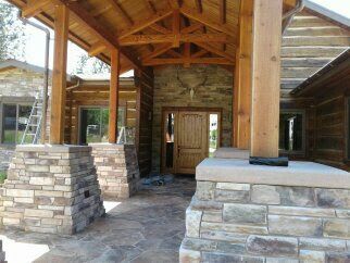 Wooden lodge entrance with stone columns and a covered porch