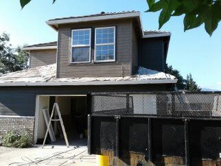 House under construction with ladder, scaffolding, and black construction fencing in front