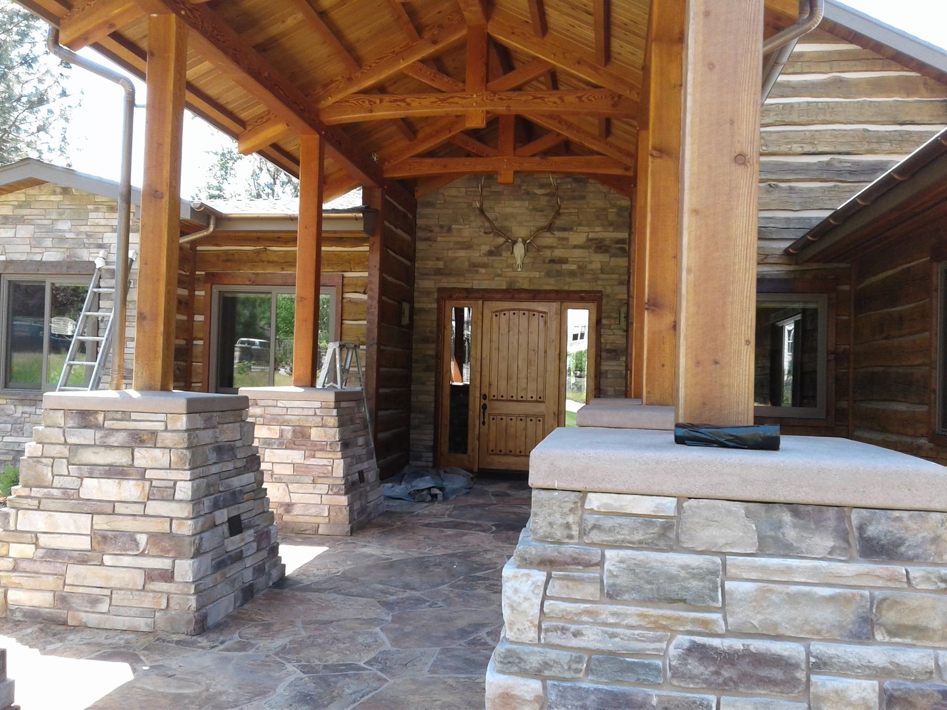 Covered stone-and-wood porch with timber beams and a rustic wooden front door