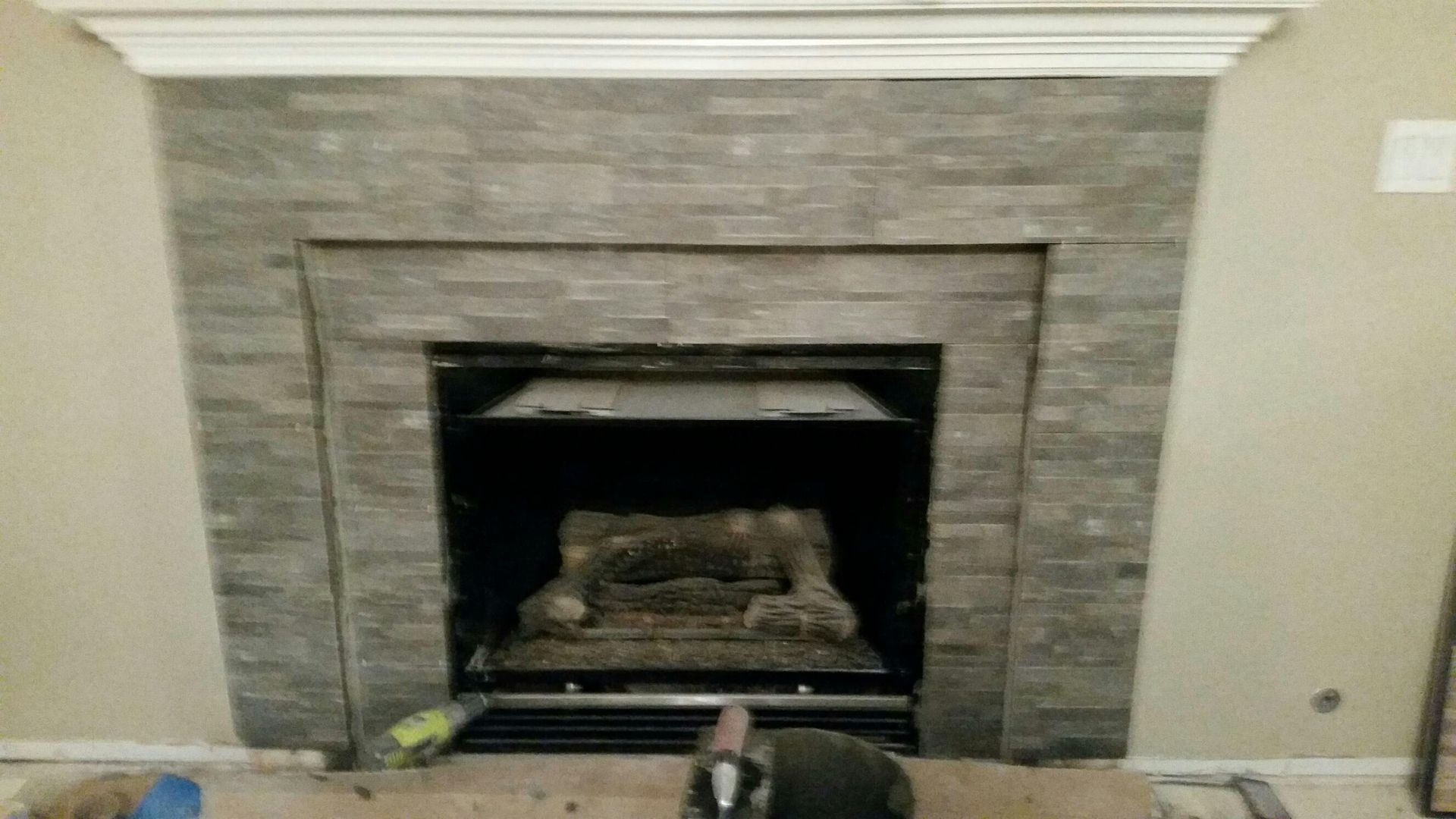 Stone fireplace with a black firebox and beige wall, centered in a living room.