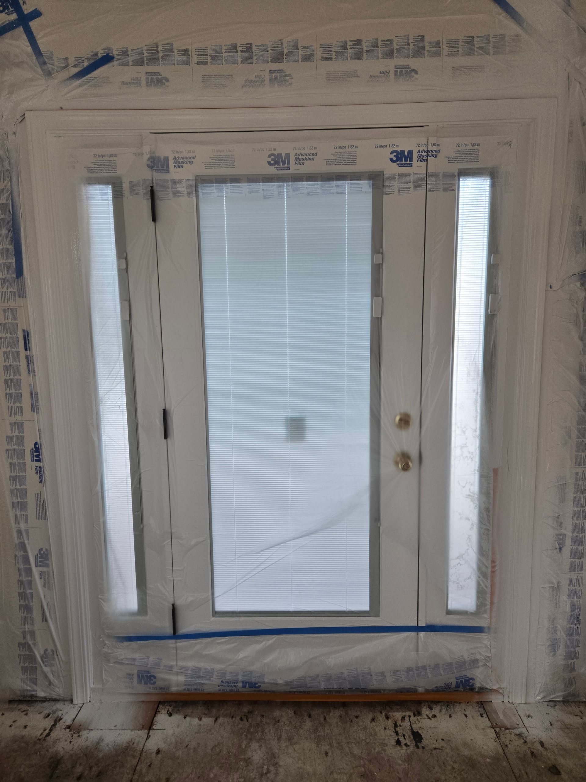 Painted front door with sidelights and a frosted glass panel, surrounded by unfinished wall trim.