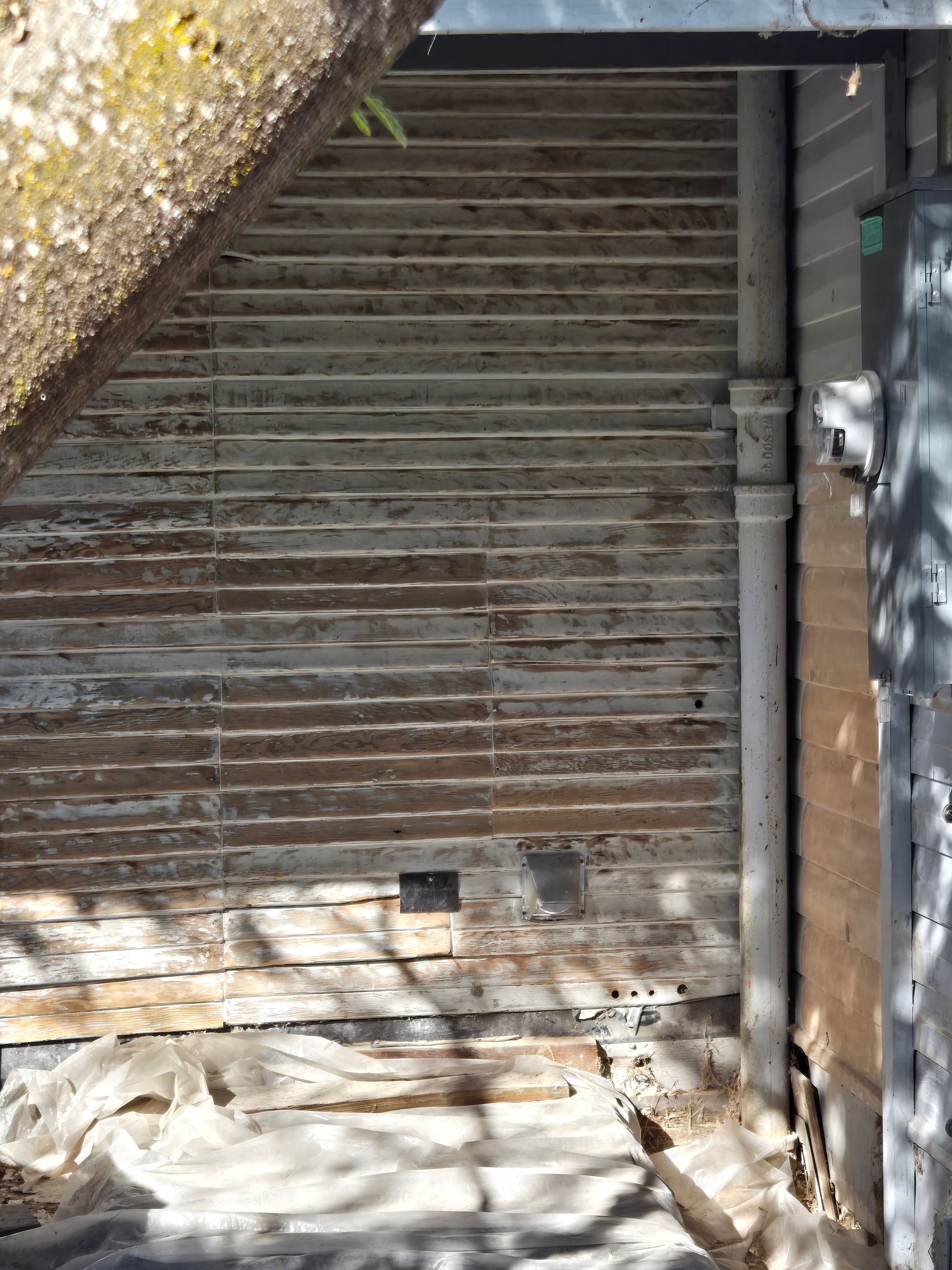 Closed metal roll-up door in a worn, dimly lit alleyway with a concrete floor and wall pipes