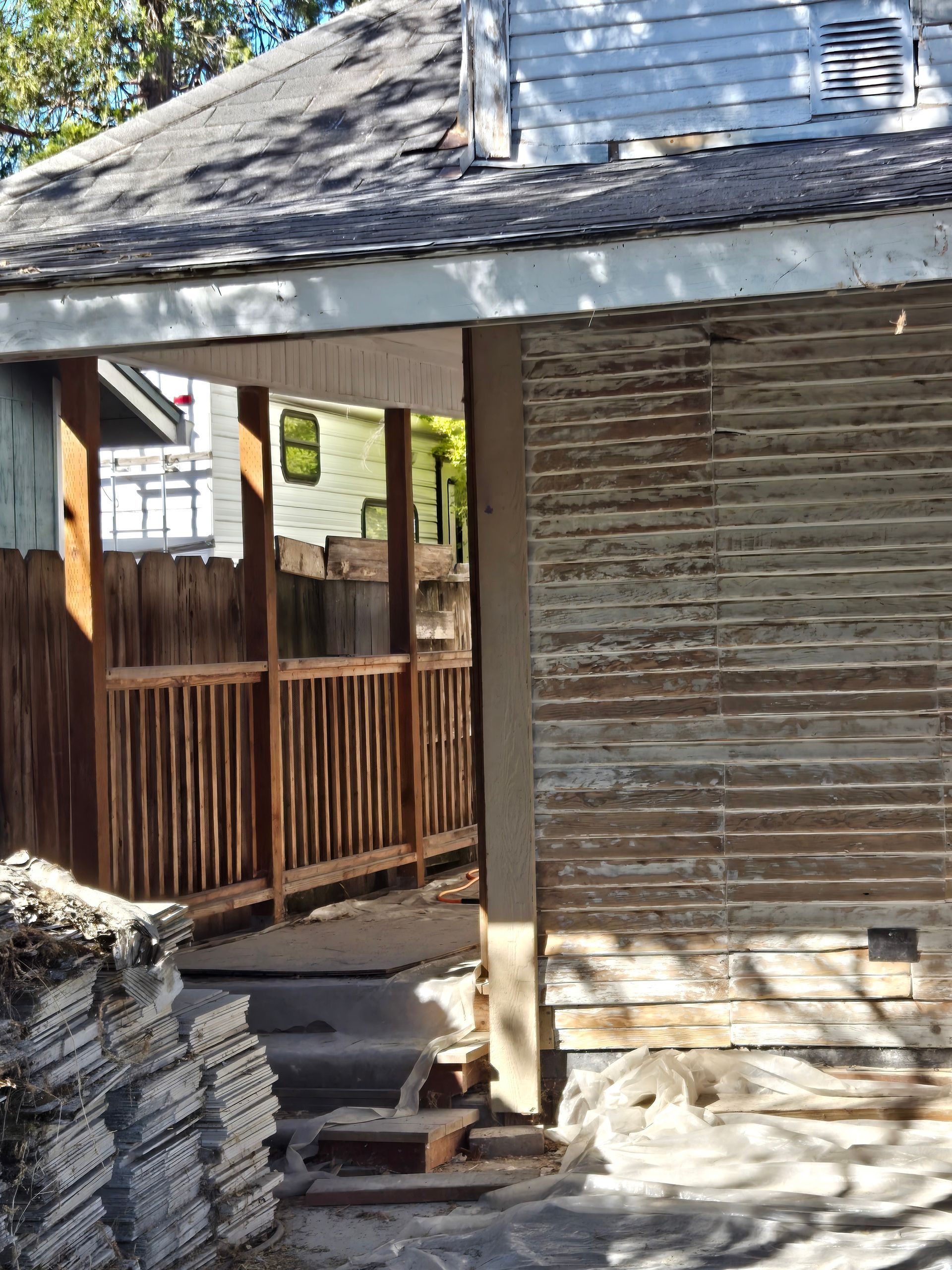 Wooden gazebo with weathered siding and railings, beside stacked stone tiles in a rustic outdoor setting