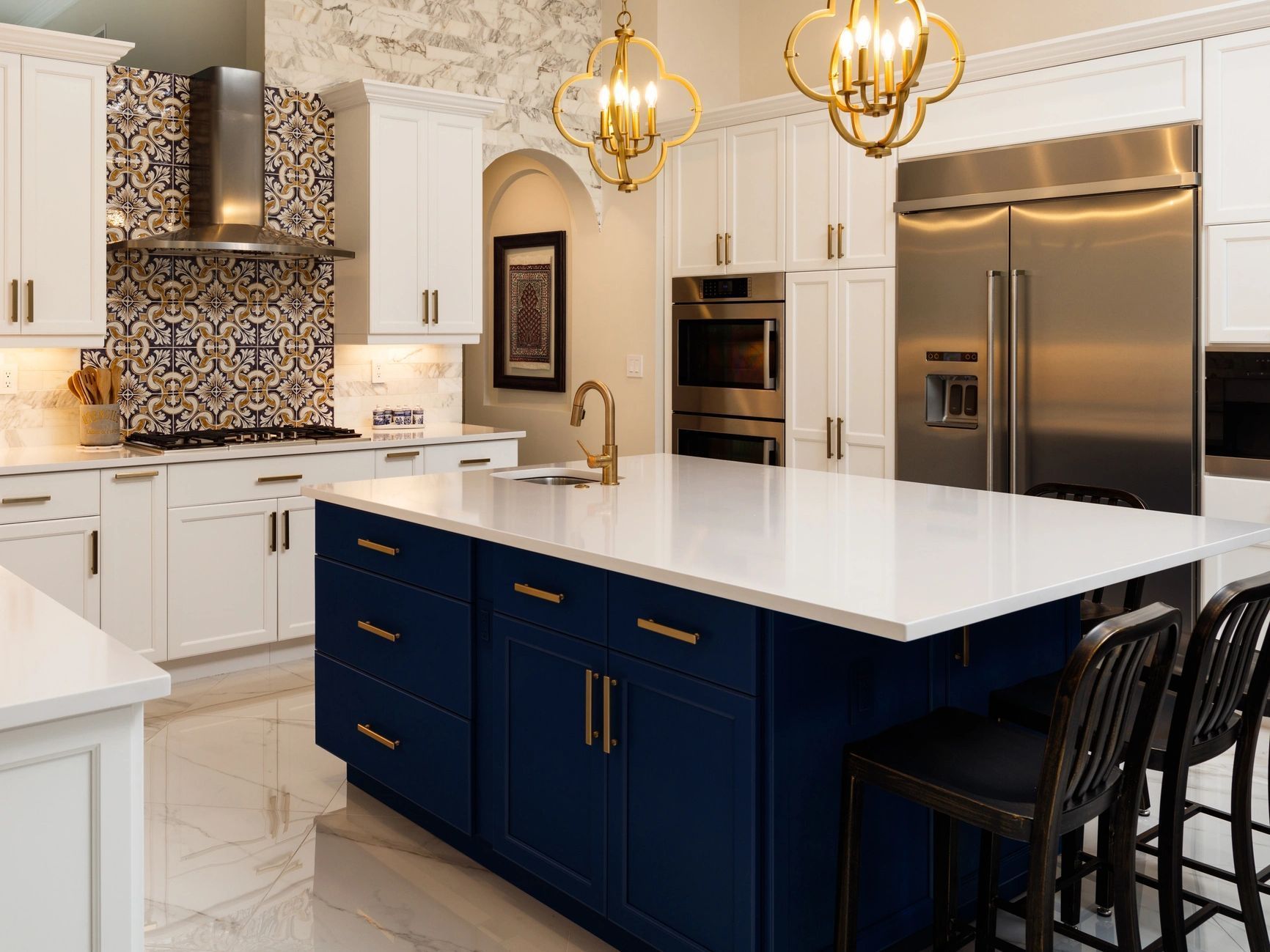 Modern kitchen with white cabinets, navy island, gold pendant lights, and stainless steel appliances