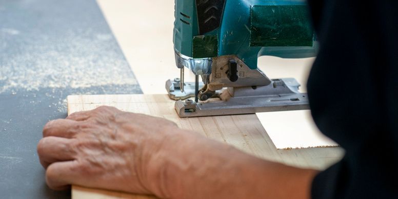 Hands guiding a sewing machine stitching light fabric on a worktable