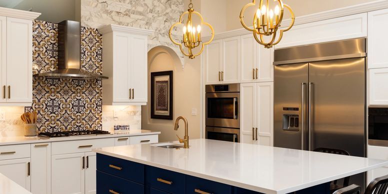 Modern kitchen with white cabinets, marble island, blue tile backsplash, and gold pendant lights