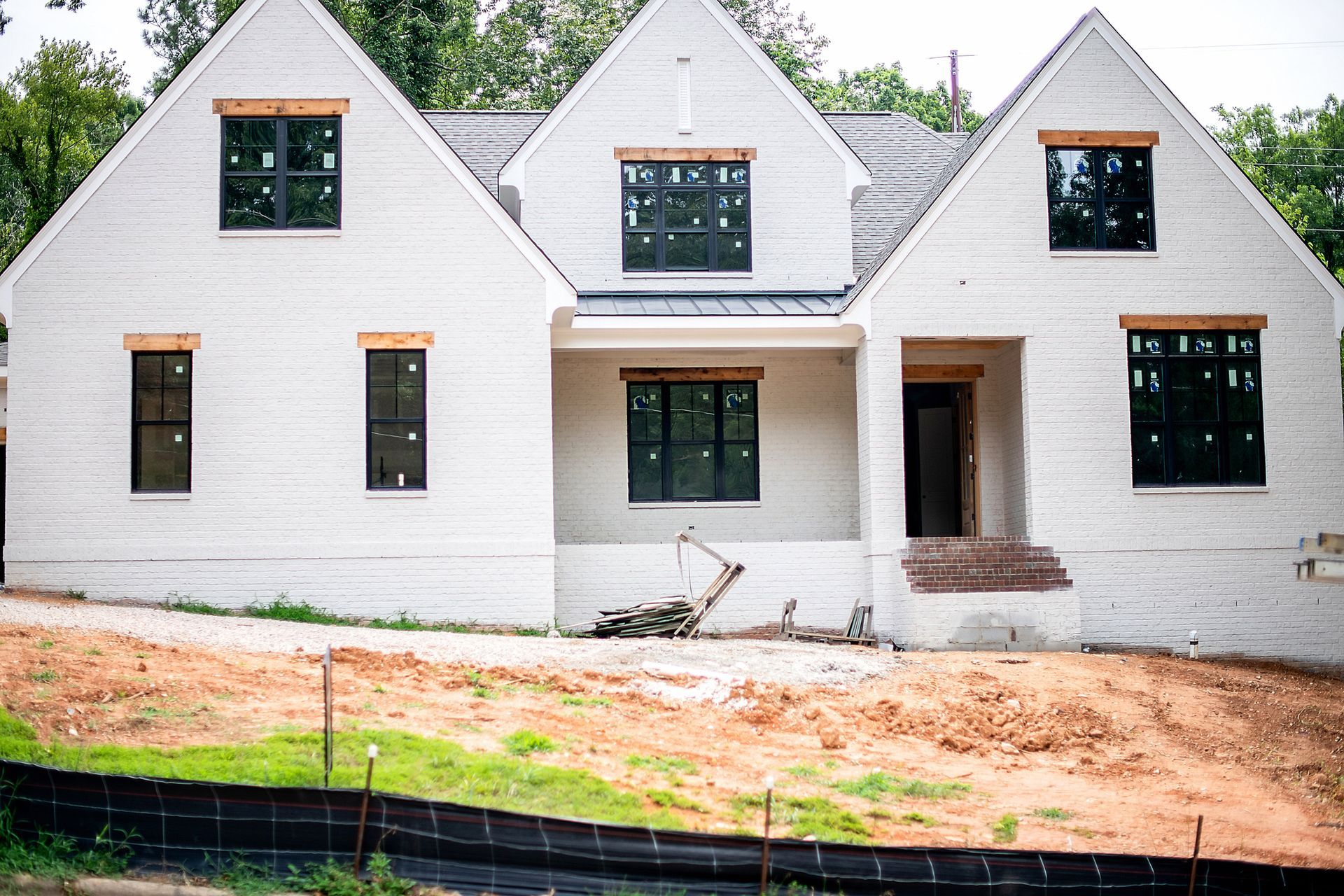 White house under construction with black windows and a brick entryway.