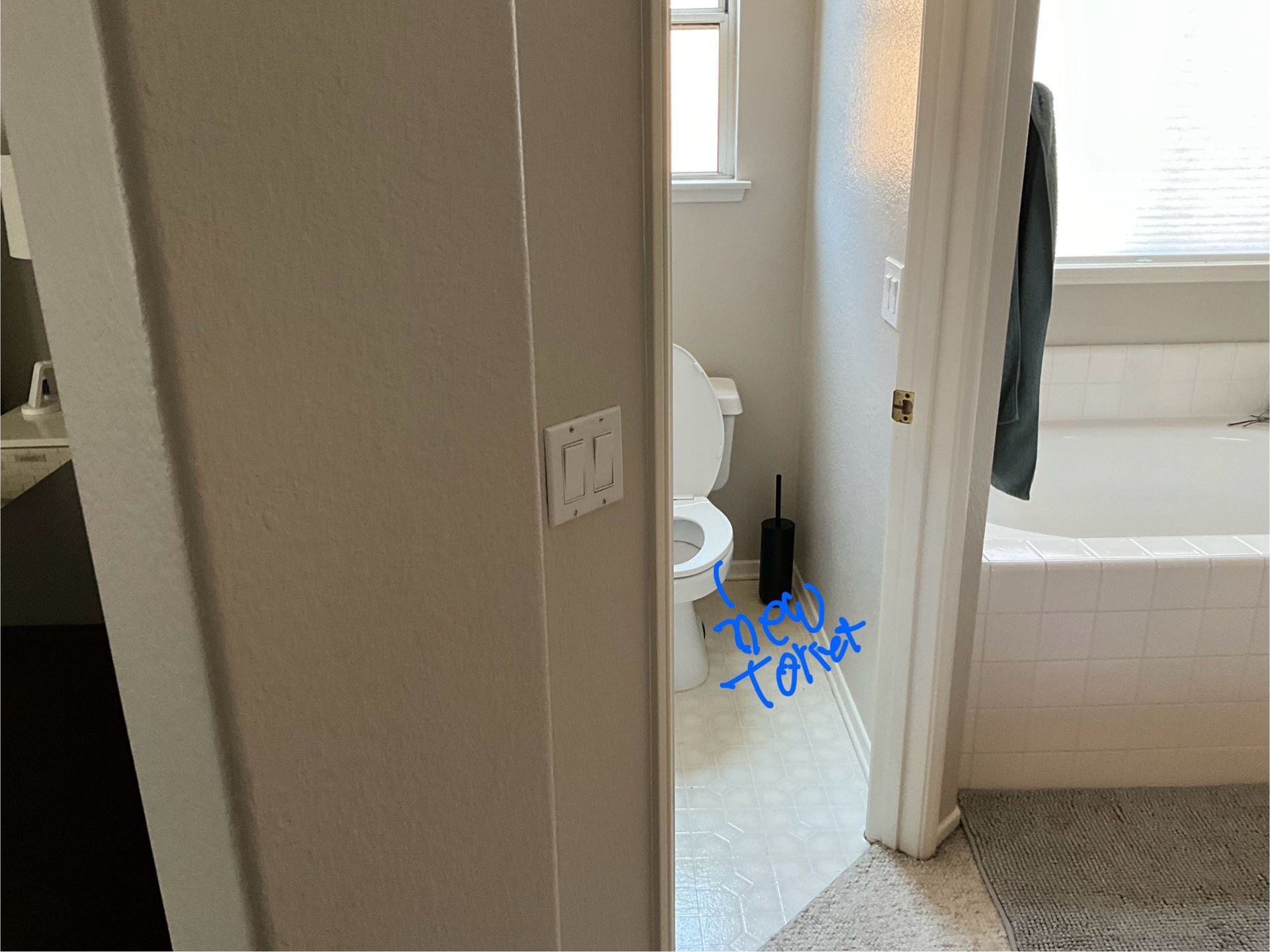 Bathroom with toilet, a partially visible tub, and an open door.