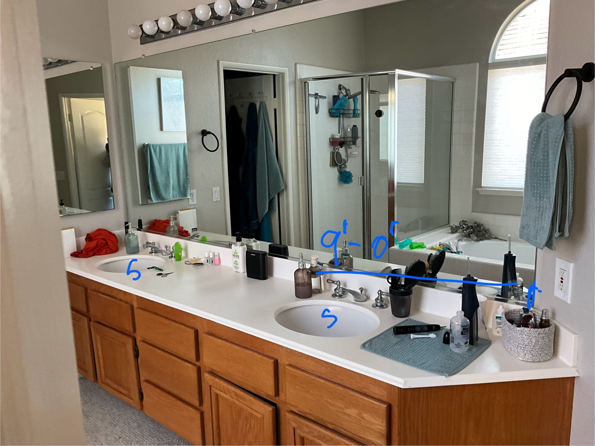 Bathroom with double sinks, large mirror, and brown cabinets. A towel hangs on the wall.