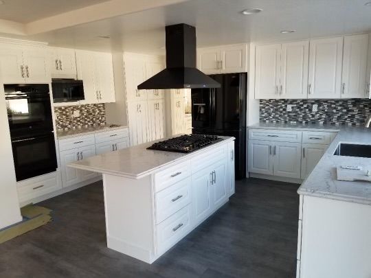 White kitchen with island, black appliances, and mosaic backsplash.