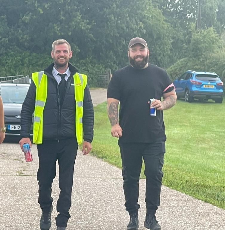 two men are walking down a road with a car in the background