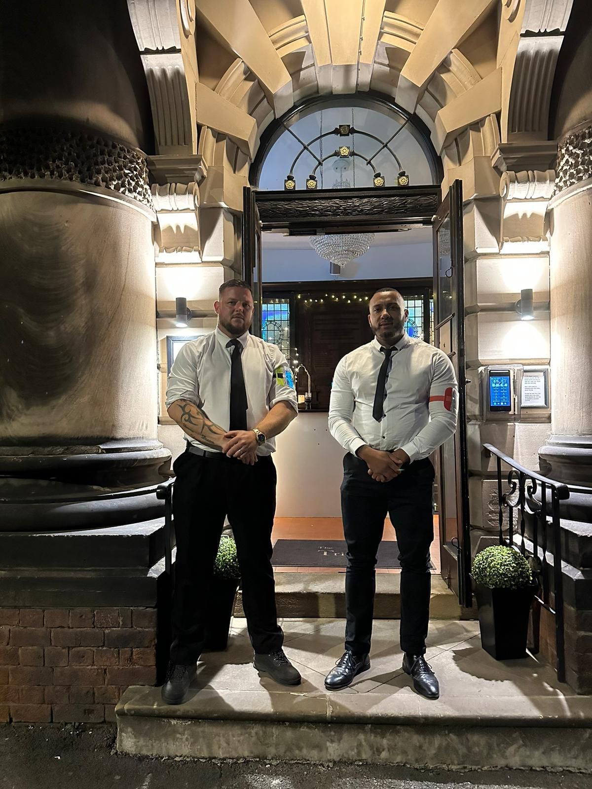two men in suits and ties are standing in front of a building .