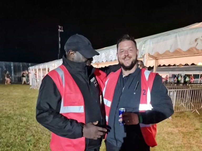 two men in red vests are posing for a picture