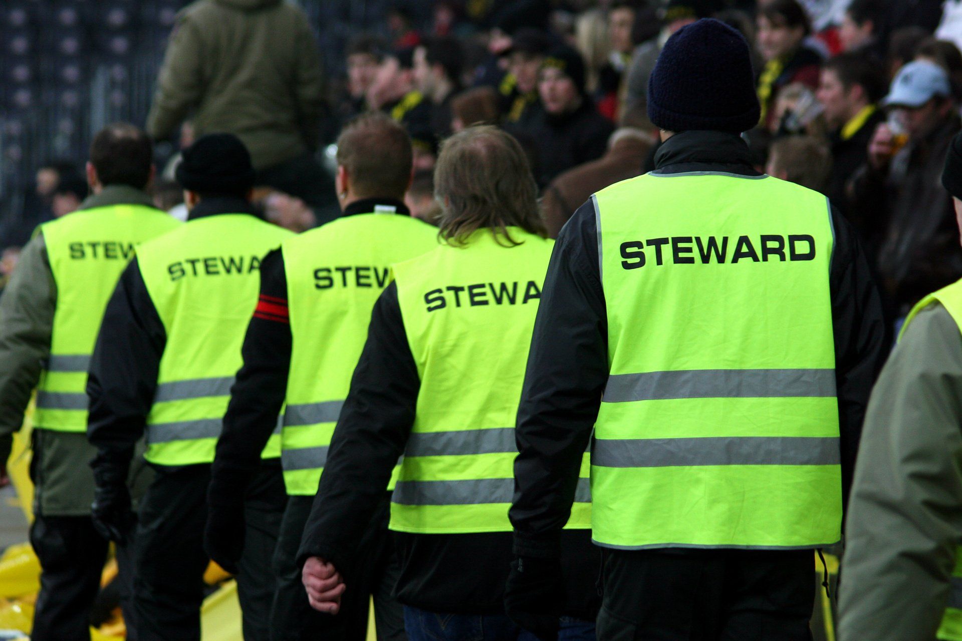 A group of people wearing yellow vests that say steward