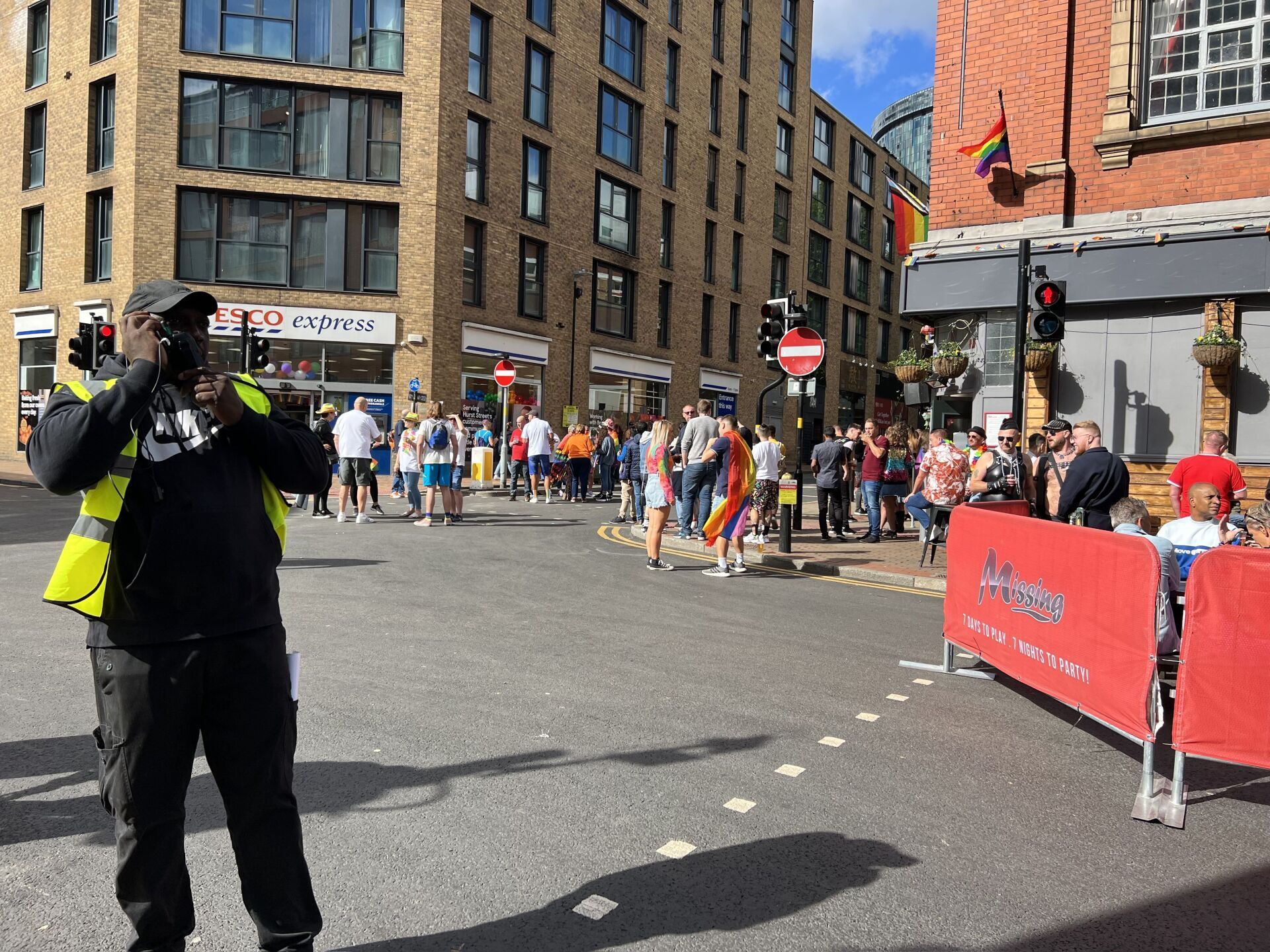 A man is taking a picture of a crowd of people on a street corner.