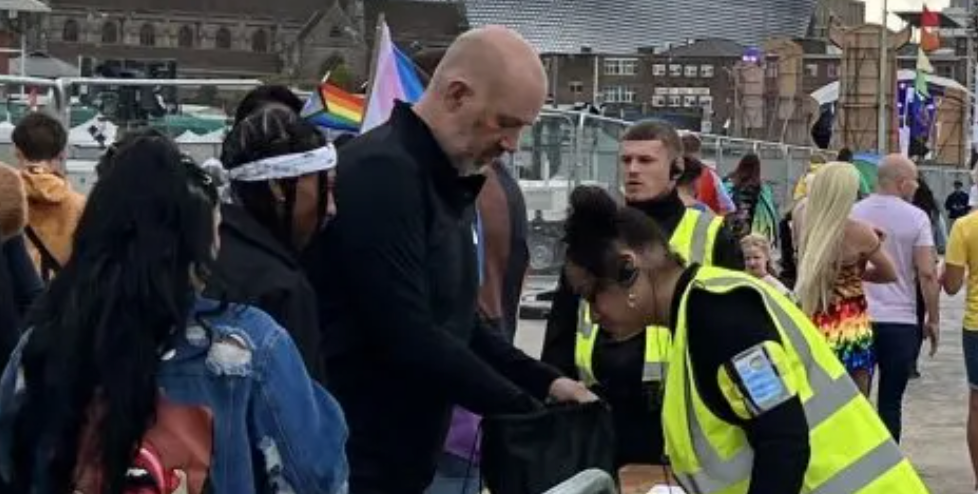 a group of people are standing around a table in a parking lot .