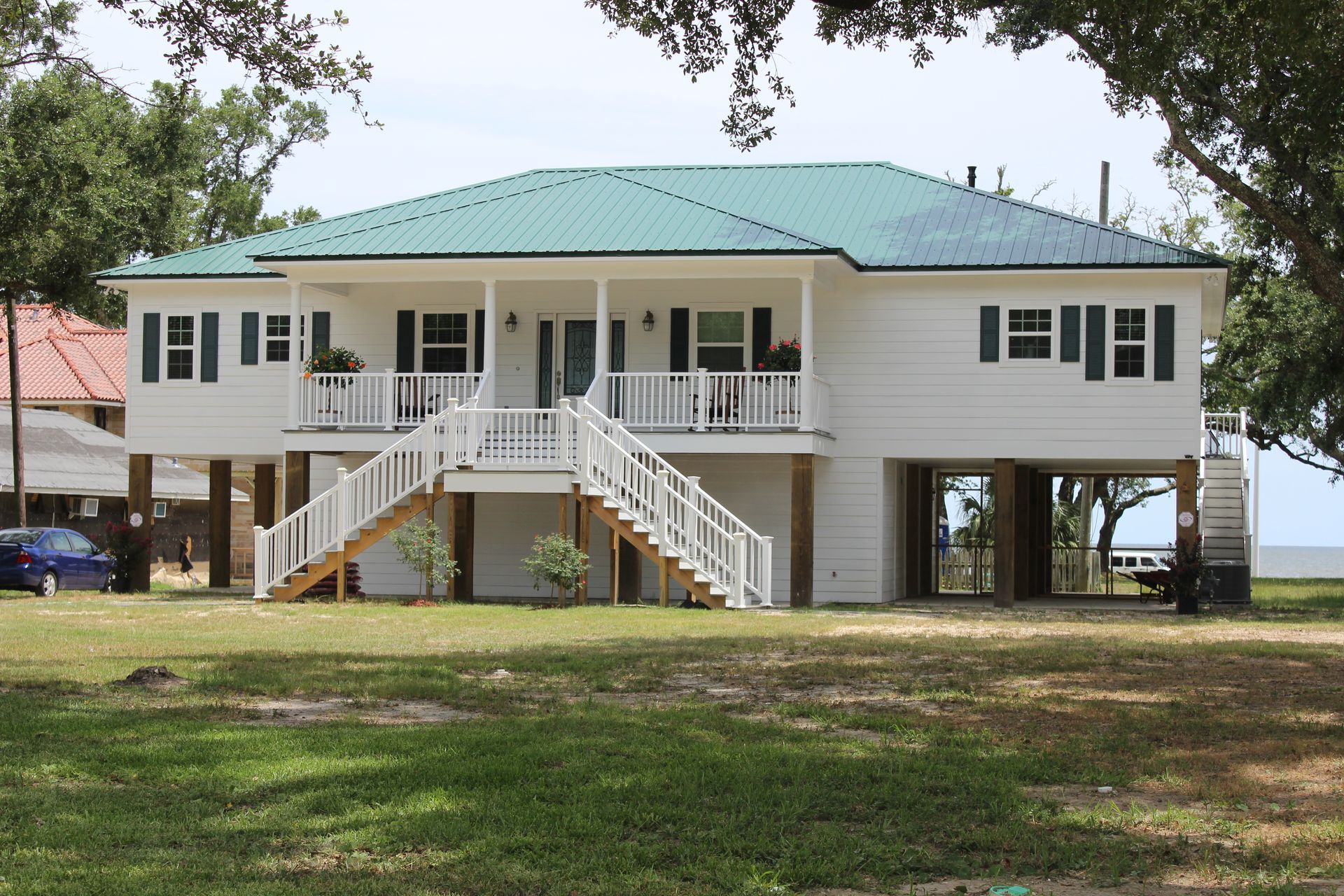A white house with a green roof and stairs