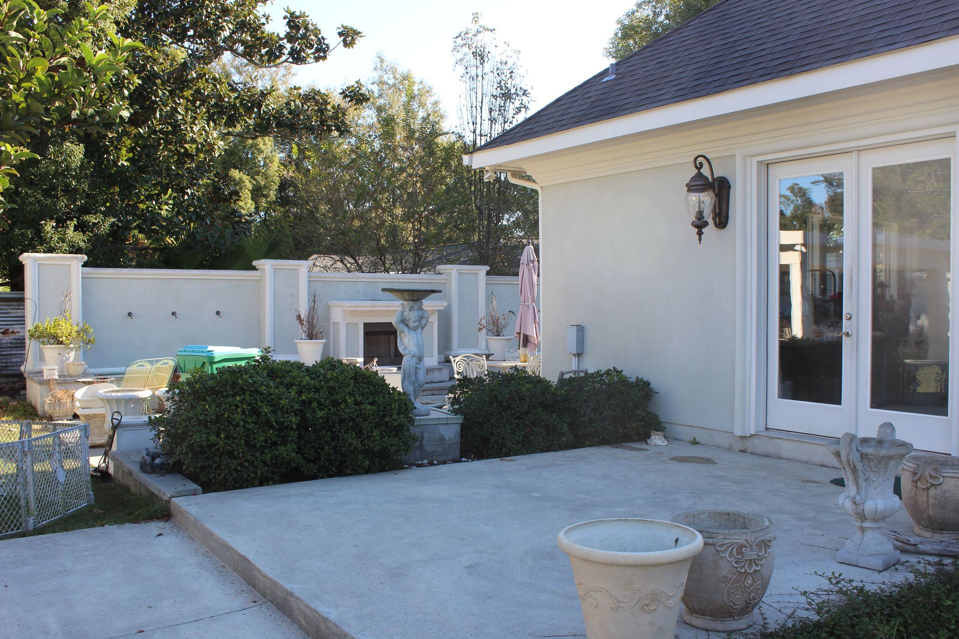 A man is kneeling down in a kitchen fixing a refrigerator.