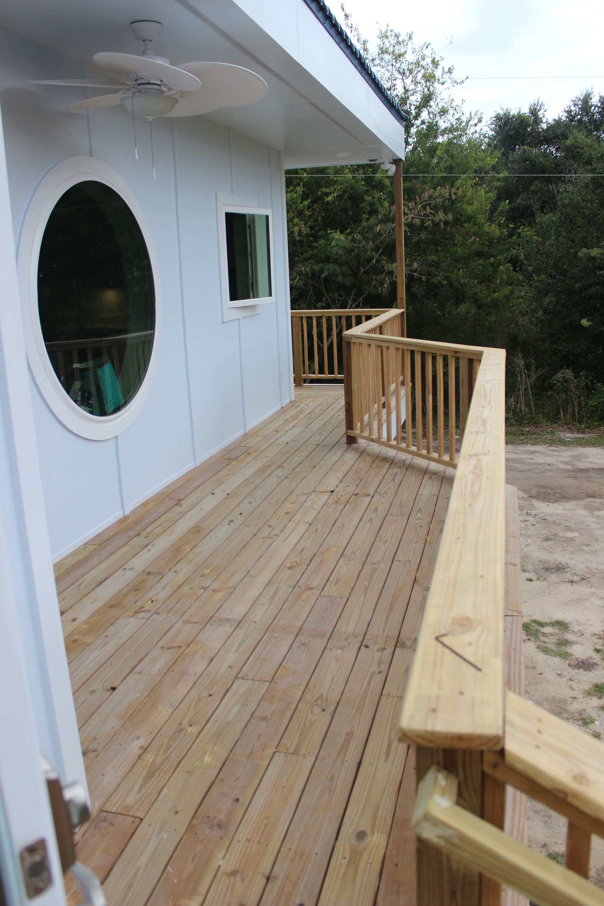 A white house with a wooden deck and a round window