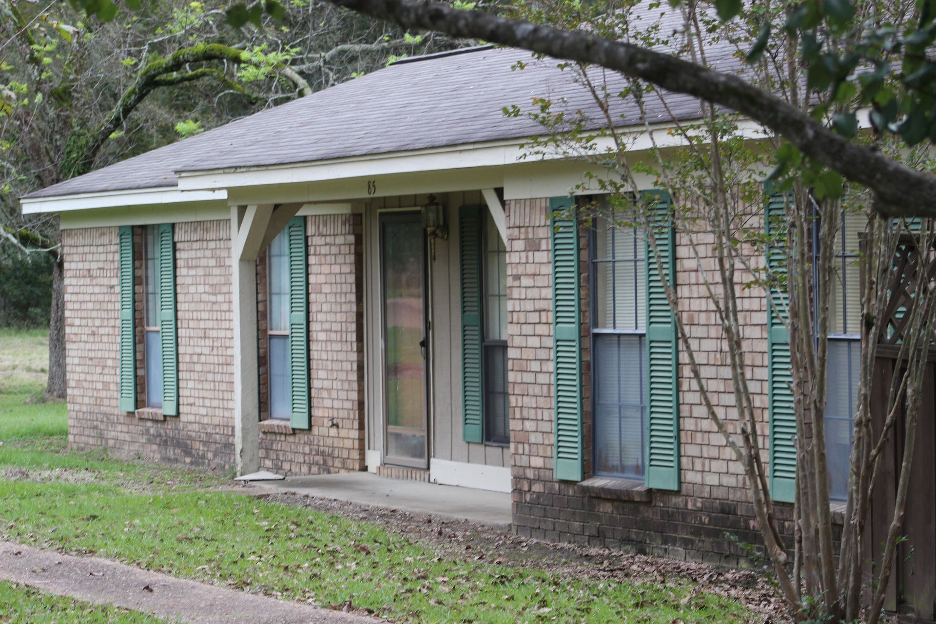 A small brick house with green shutters on the windows