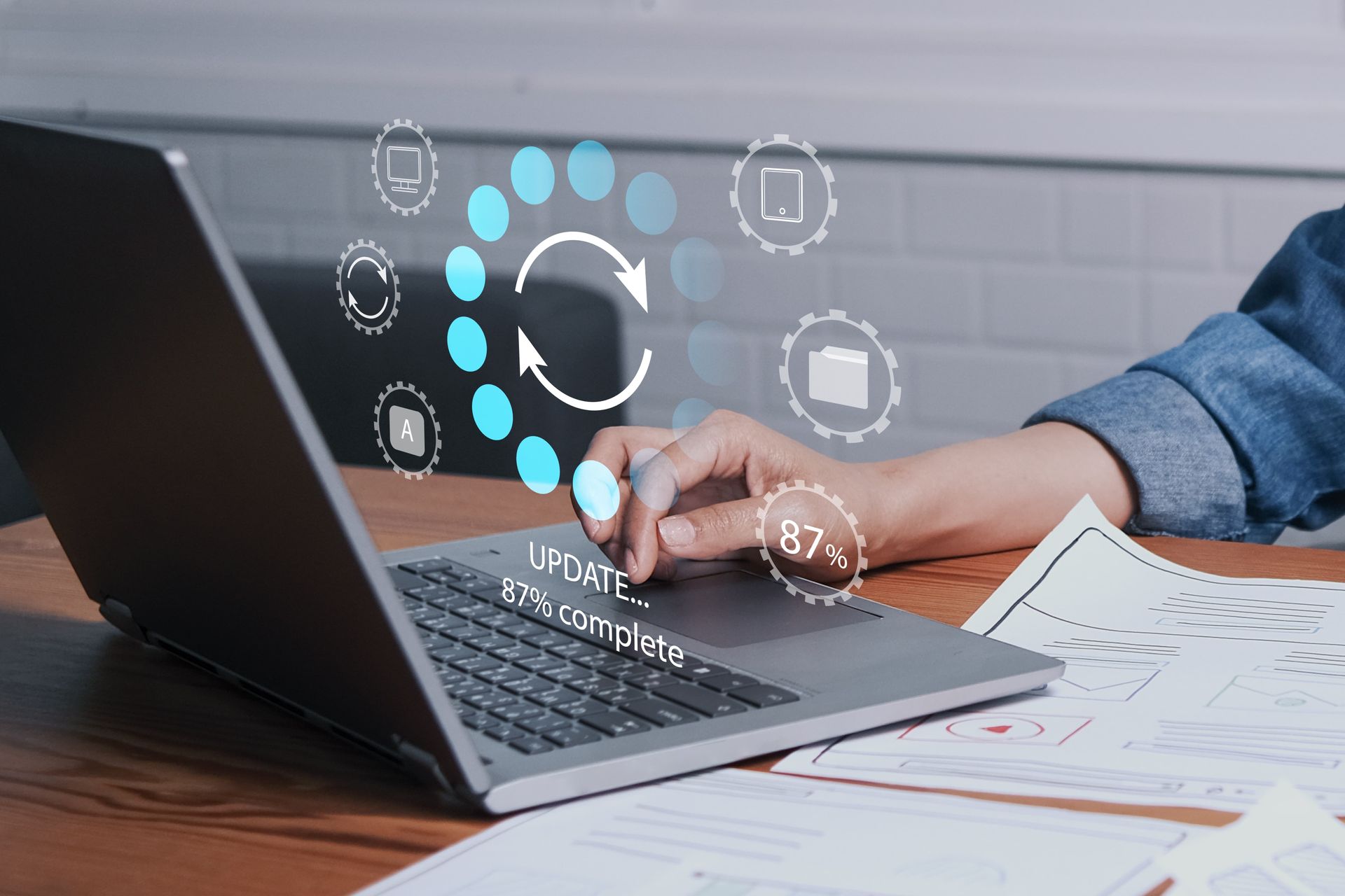 Laptop updating software, displaying a progress bar, near a person's hand.