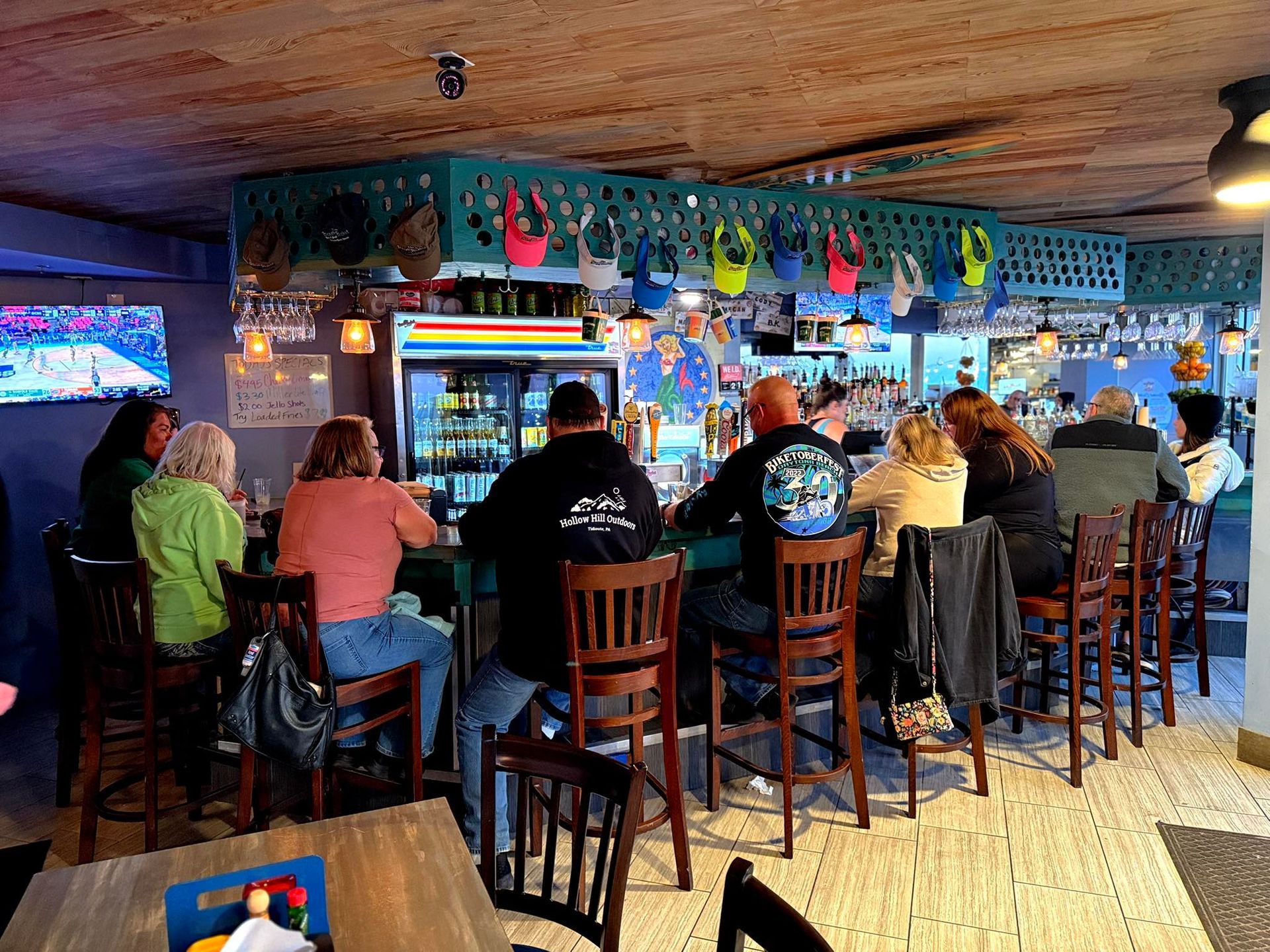 Bar patrons seated at a counter. Drinks and glassware on the counter. Bright, colorful decor.