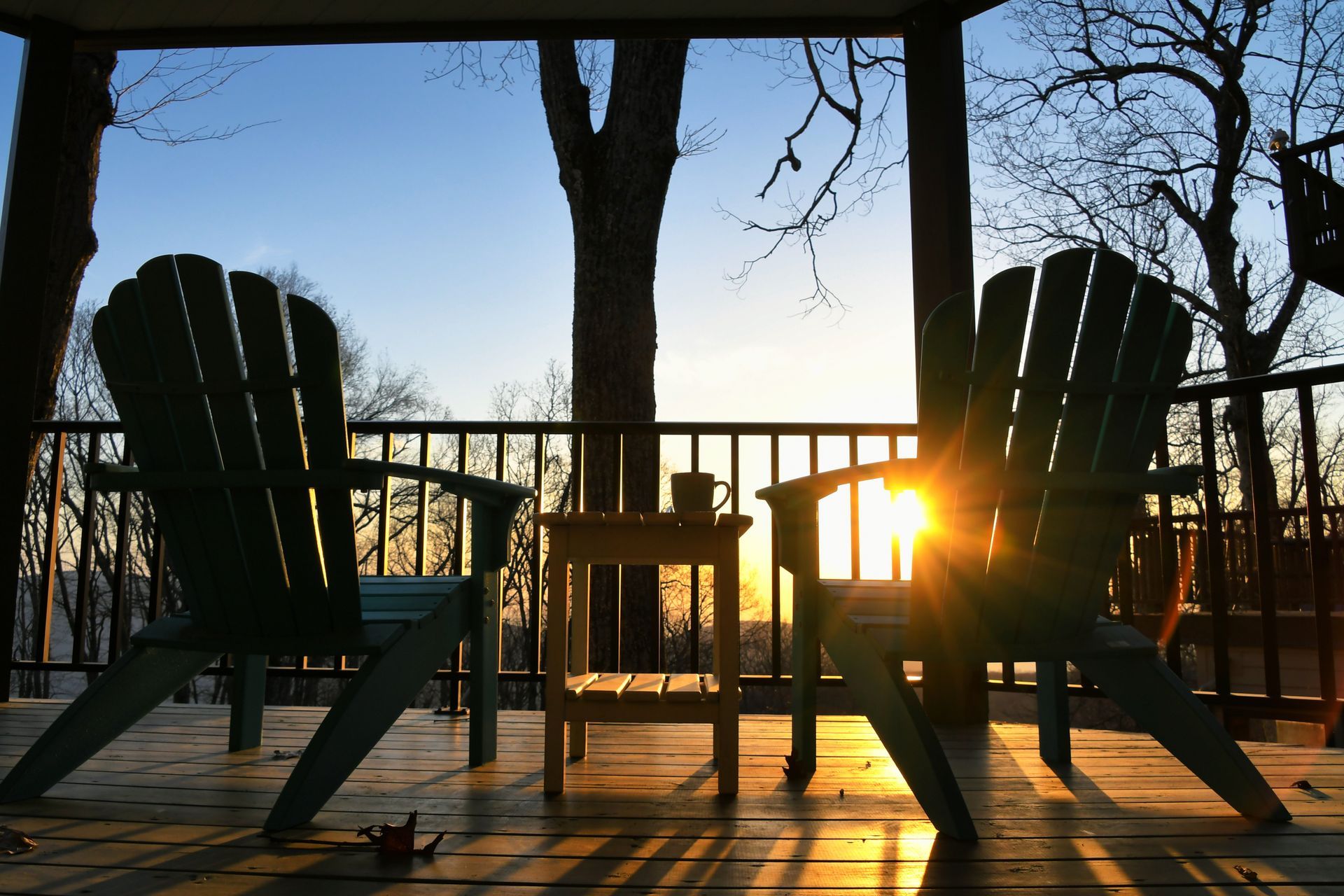 Wood deck with seating area overlooking wooded hills in the Ozarks during sunrise