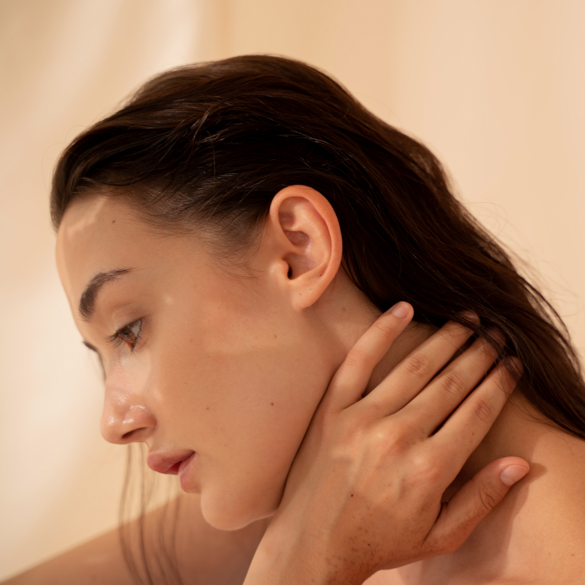 A close up of a woman 's face with her hand on her neck