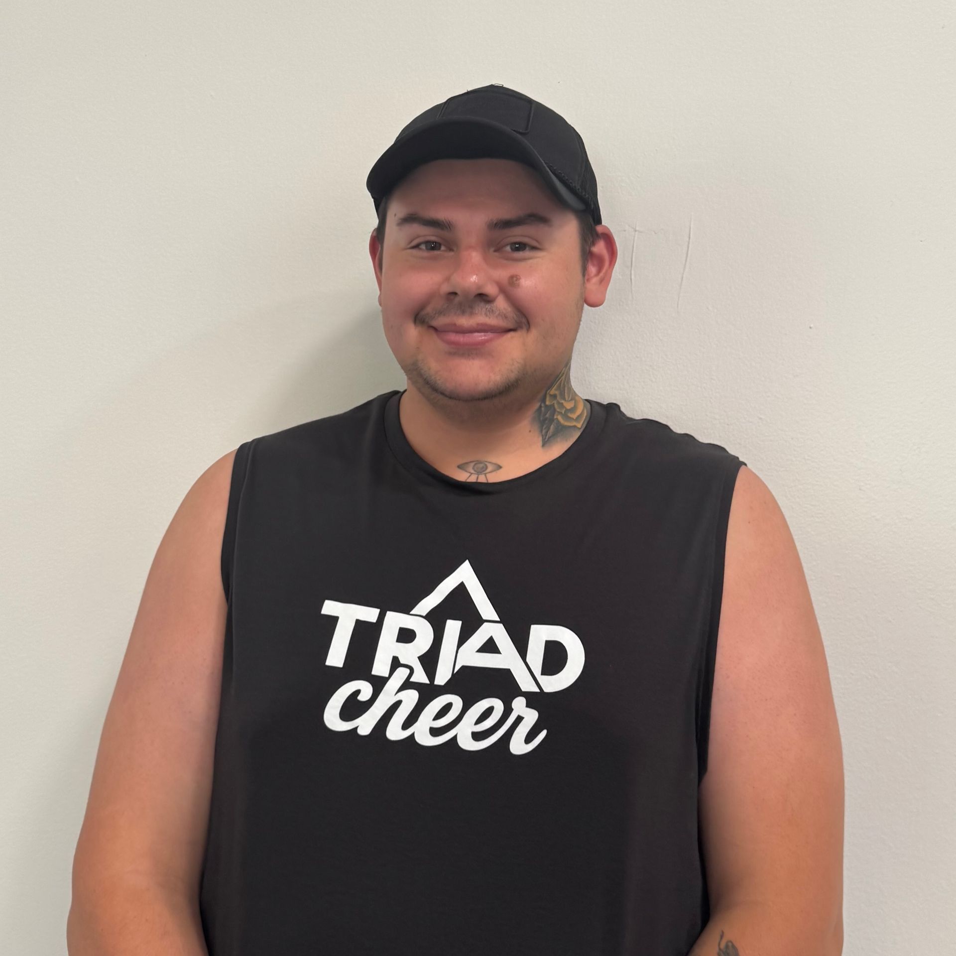 Man wearing a black cap and tank top that says 