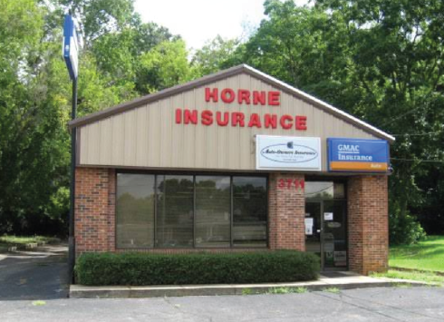The Horne Insurance office building with a brick facade and tan siding, set in a wooded area.