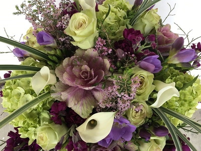 A close up of a bouquet of purple and green flowers on a table.