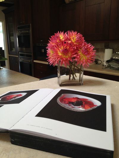 A vase of flowers sits on a table next to a book