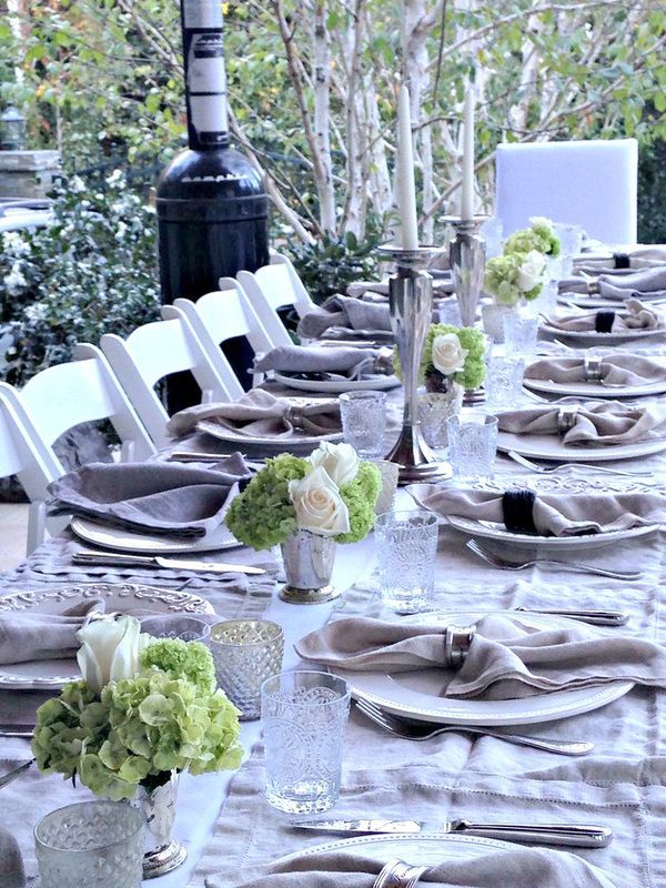 A long table with plates , napkins , candles and flowers on it.