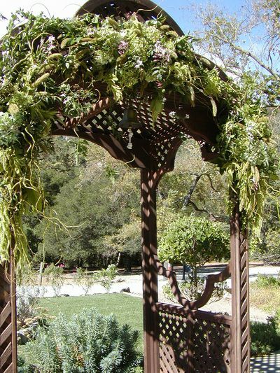 A wooden gazebo decorated with greenery and flowers