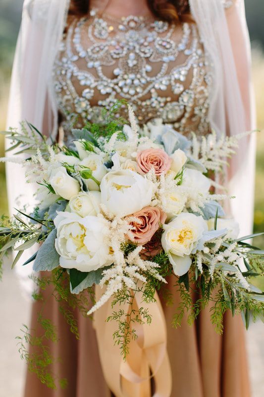 A bride in a wedding dress is holding a bouquet of flowers.