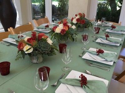 A long table with plates , glasses , napkins and flowers on it.