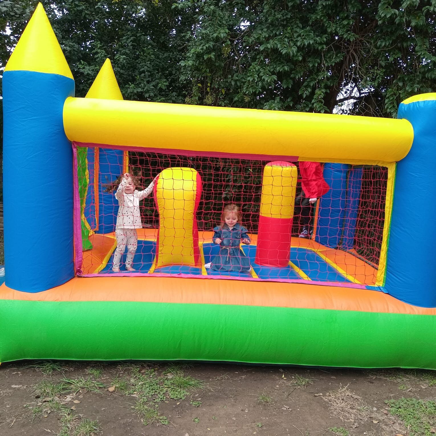 Castillo hinchable colorido con dos niños jugando dentro al aire libre